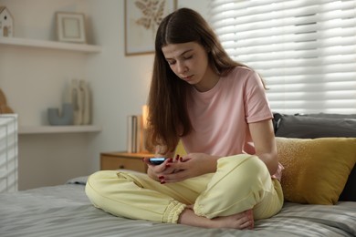 Photo of Upset teenage girl on bed at home