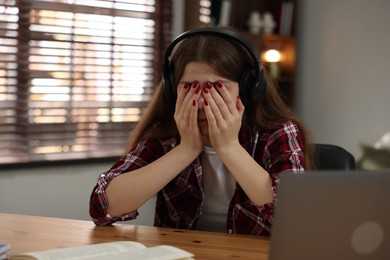 Photo of Stressed teenage girl studying at desk indoors