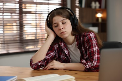 Photo of Stressed teenage girl studying at desk indoors