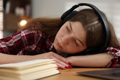 Photo of Stressed teenage girl studying at desk indoors
