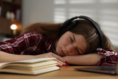 Photo of Stressed teenage girl studying at desk indoors