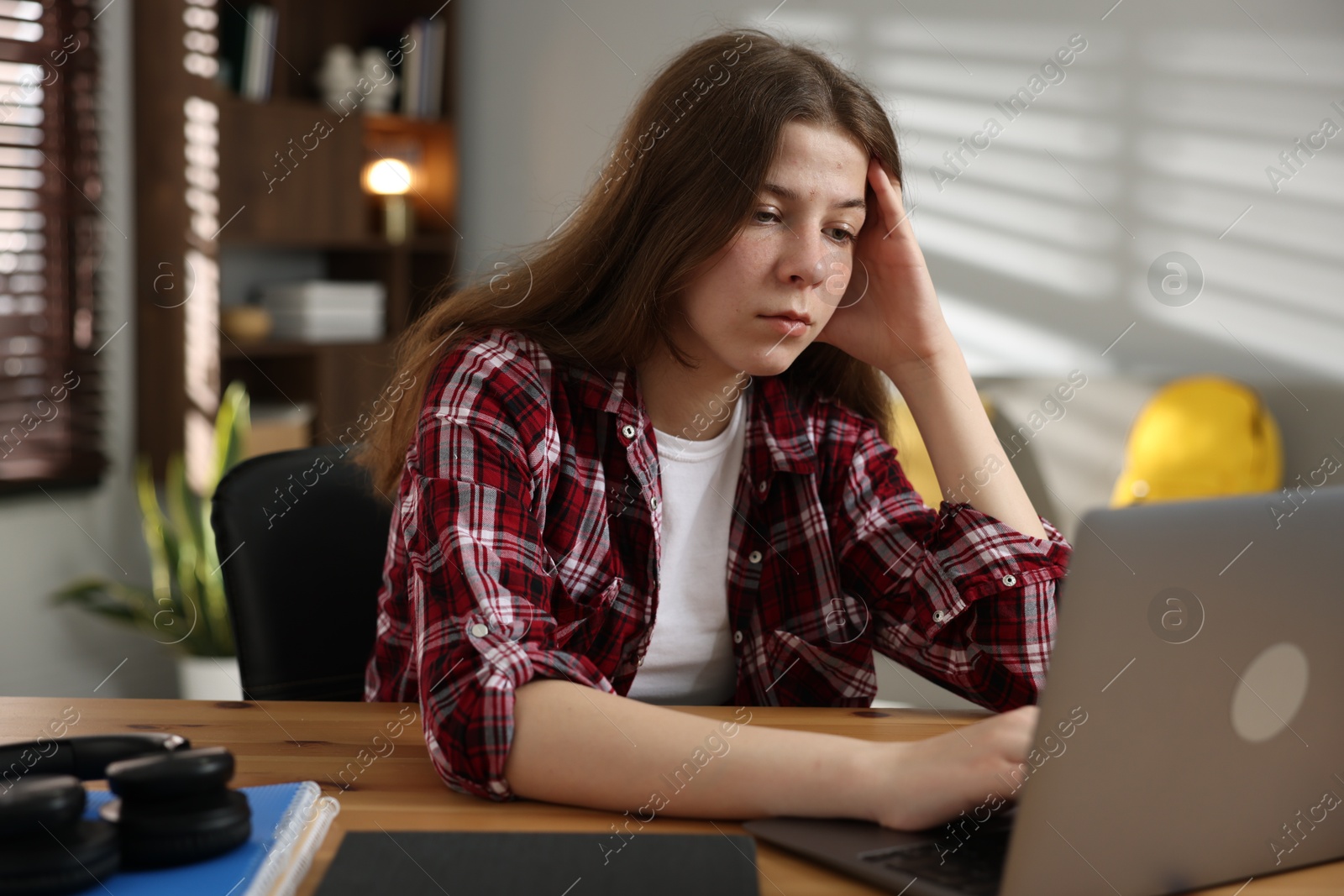 Stressed teenage girl studying at desk indoors Photo of Stressed teenage girl studying at desk indoors