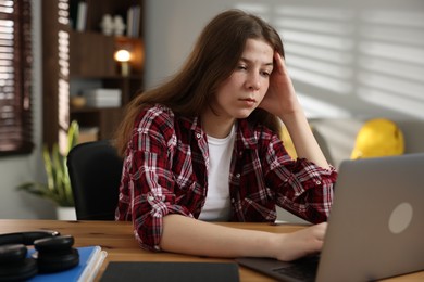 Photo of Stressed teenage girl studying at desk indoors