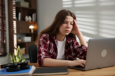 Photo of Stressed teenage girl studying at desk indoors