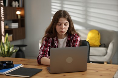 Photo of Stressed teenage girl studying at desk indoors
