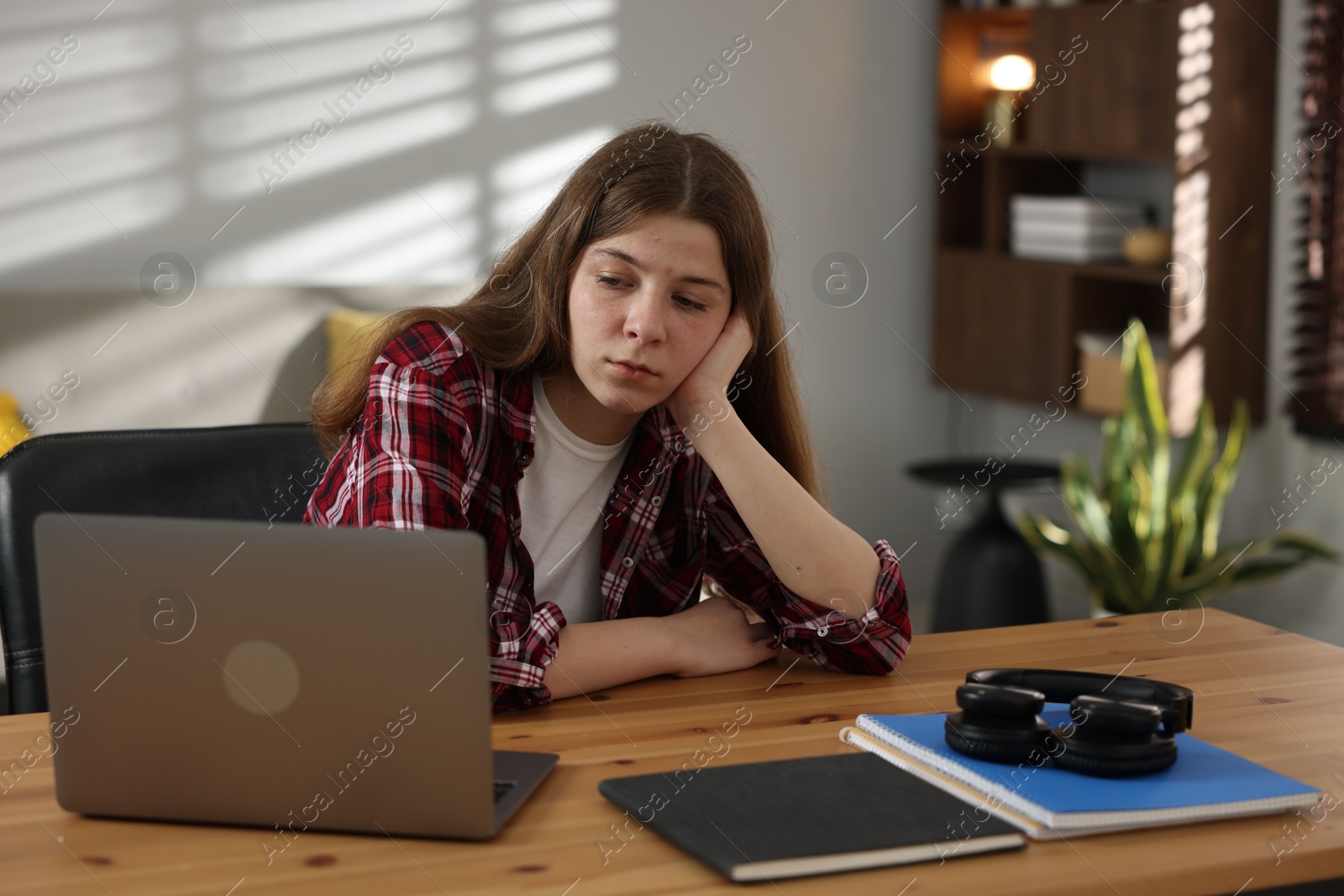Stressed teenage girl studying at desk indoors Photo of Stressed teenage girl studying at desk indoors