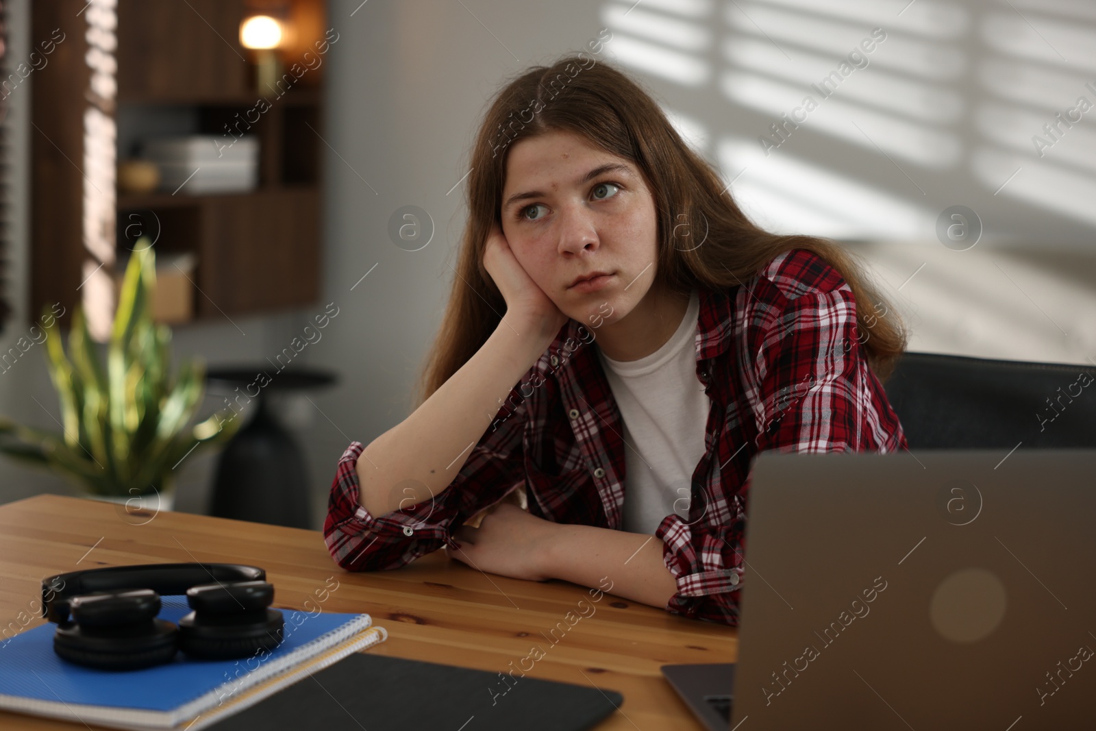 Stressed teenage girl studying at desk indoors Photo of Stressed teenage girl studying at desk indoors
