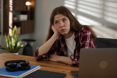 Photo of Stressed teenage girl studying at desk indoors