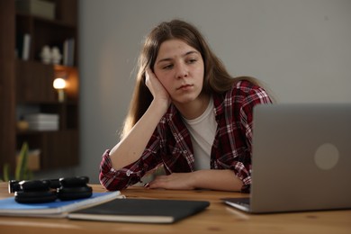 Photo of Stressed teenage girl studying at desk indoors