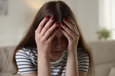 Photo of Depressed teenage girl on sofa at home