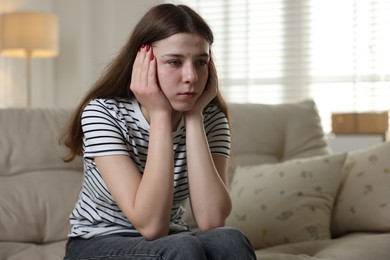 Photo of Depressed teenage girl on sofa at home. Space for text