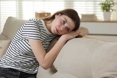 Photo of Depressed teenage girl on sofa at home