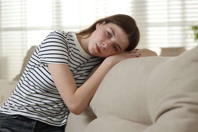 Photo of Depressed teenage girl on sofa at home