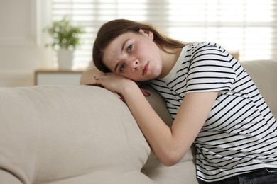 Photo of Depressed teenage girl on sofa at home