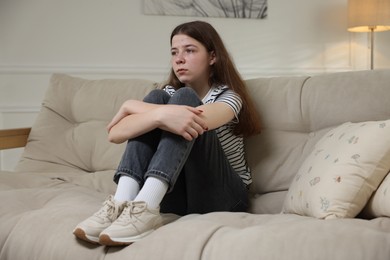 Photo of Depressed teenage girl on sofa at home