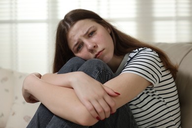 Photo of Depressed teenage girl on sofa at home