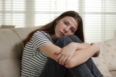 Photo of Depressed teenage girl on sofa at home
