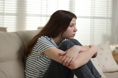 Photo of Depressed teenage girl on sofa at home
