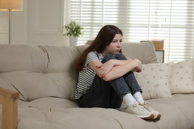 Photo of Depressed teenage girl on sofa at home