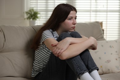 Photo of Depressed teenage girl on sofa at home