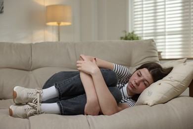 Photo of Depressed teenage girl lying on sofa at home