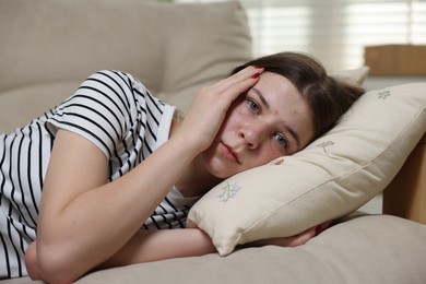 Photo of Depressed teenage girl lying on sofa at home