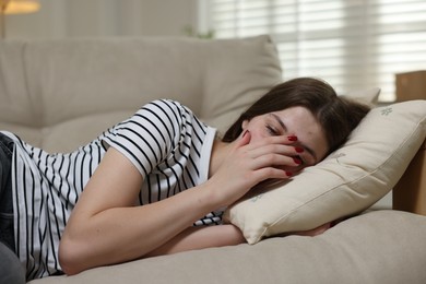 Photo of Depressed teenage girl lying on sofa at home