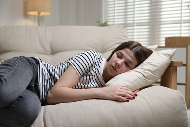 Photo of Depressed teenage girl lying on sofa at home