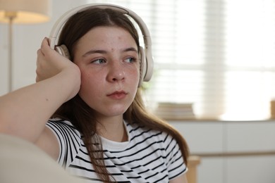 Photo of Upset teenage girl listening to music on sofa at home. Space for text