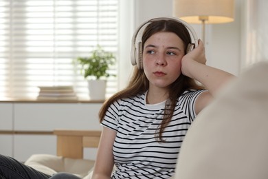 Photo of Upset teenage girl listening to music on sofa at home. Space for text