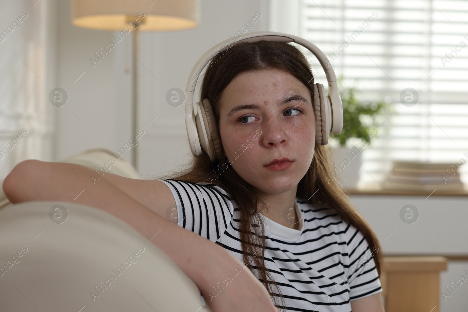Upset teenage girl listening to music on sofa at home Photo of Upset teenage girl listening to music on sofa at home