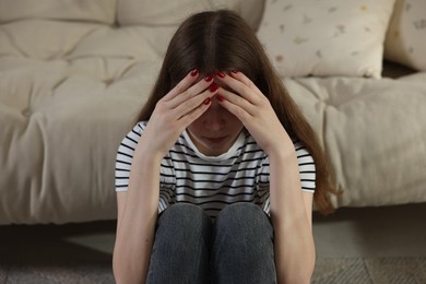 Photo of Depressed teenage girl on floor at home