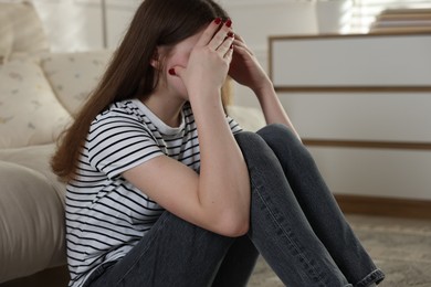Photo of Depressed teenage girl on floor at home