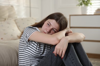 Photo of Depressed teenage girl on floor at home