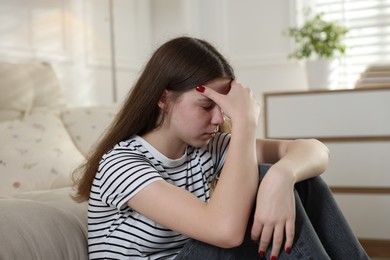 Photo of Depressed teenage girl on floor at home