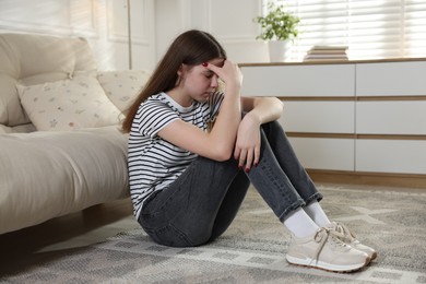 Photo of Depressed teenage girl on floor at home