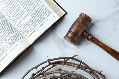 Photo of Judge's gavel, Bible and crown of thorns on white marble table, flat lay