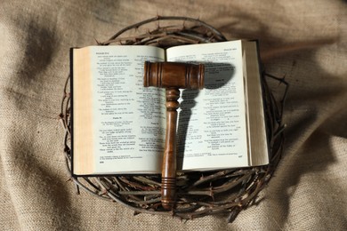 Photo of Judge's gavel, Bible and crown of thorns on burlap fabric, top view