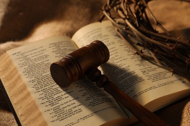 Photo of Judge's gavel, Bible and crown of thorns on burlap fabric, closeup