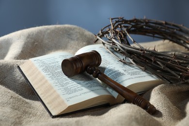 Photo of Judge's gavel, Bible and crown of thorns on burlap fabric, closeup
