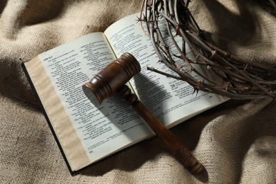 Photo of Judge's gavel, Bible and crown of thorns on burlap fabric, top view