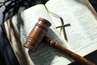 Photo of Judge's gavel, Bible and cross on black table, top view