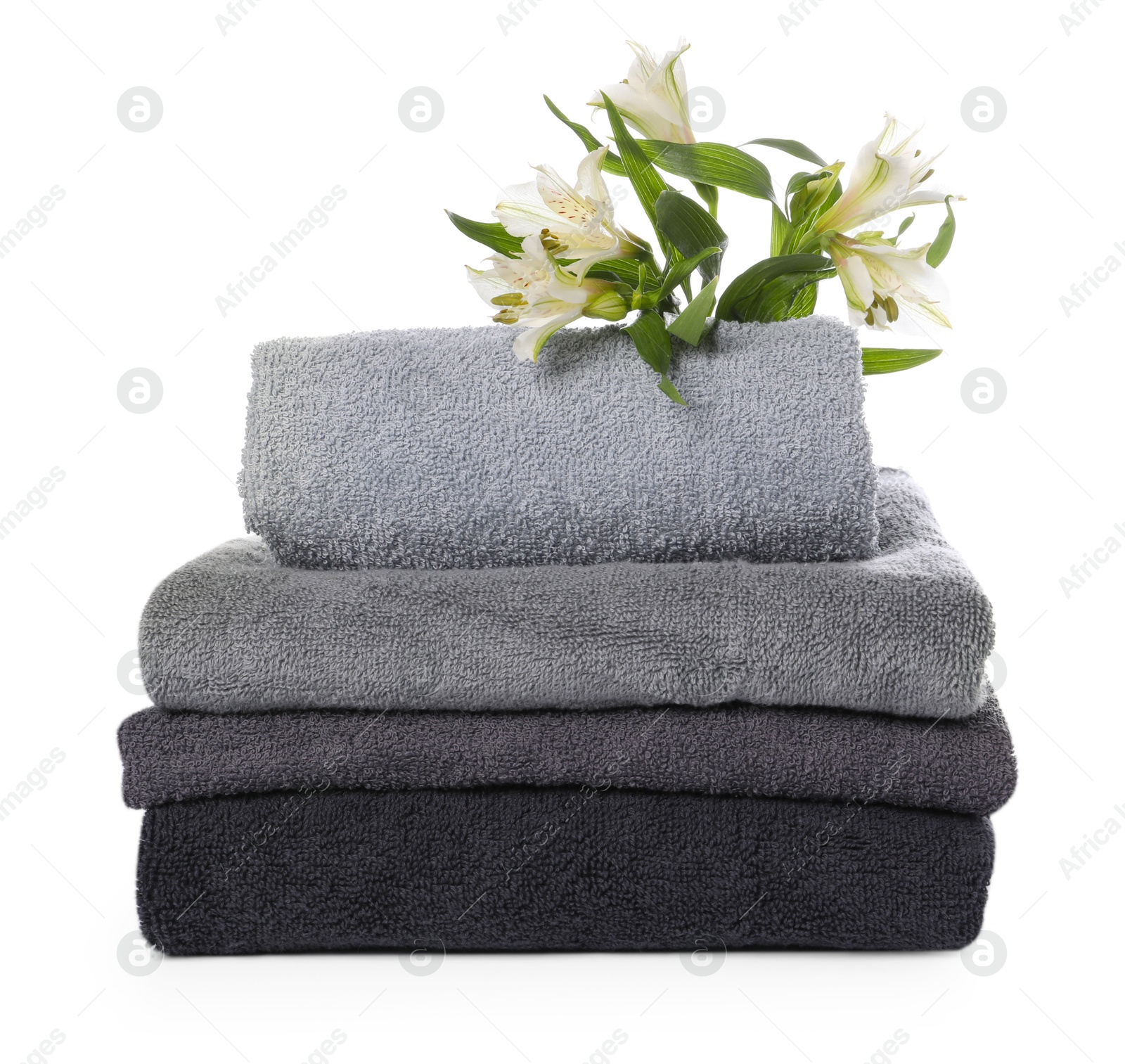 Stack of towels and beautiful flowers isolated on white Photo of Stack of towels and beautiful flowers isolated on white