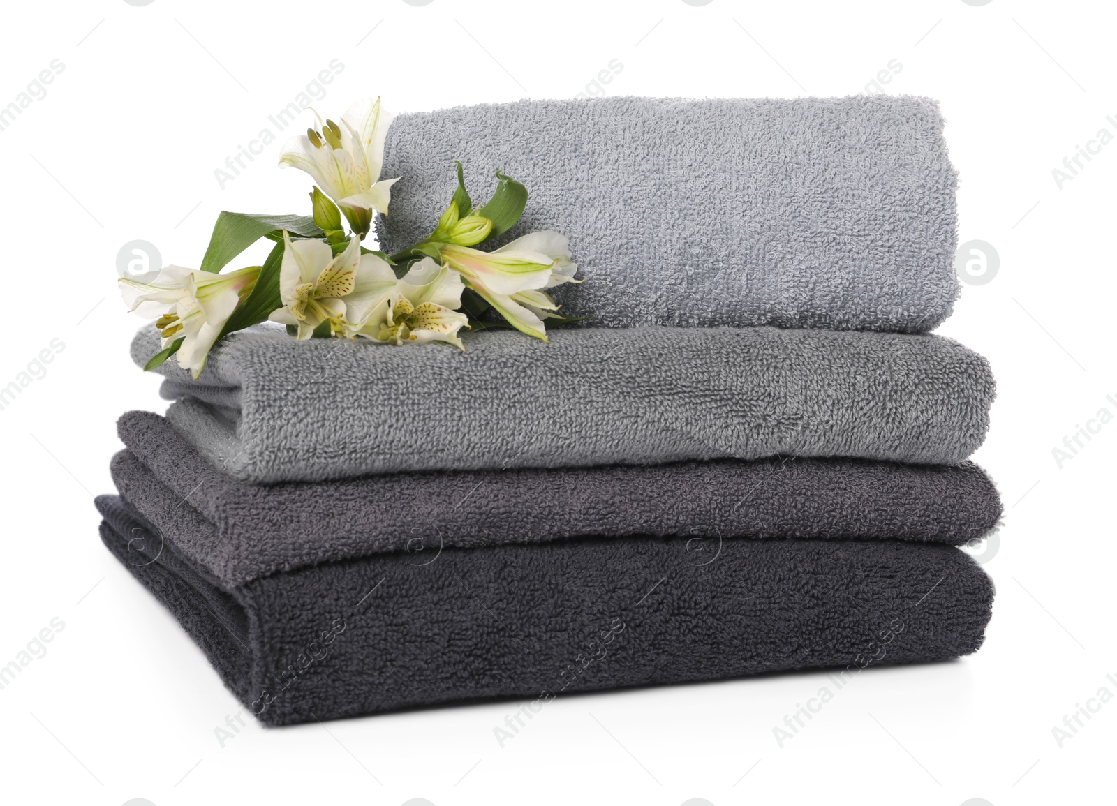 Stack of towels and beautiful flowers isolated on white Photo of Stack of towels and beautiful flowers isolated on white