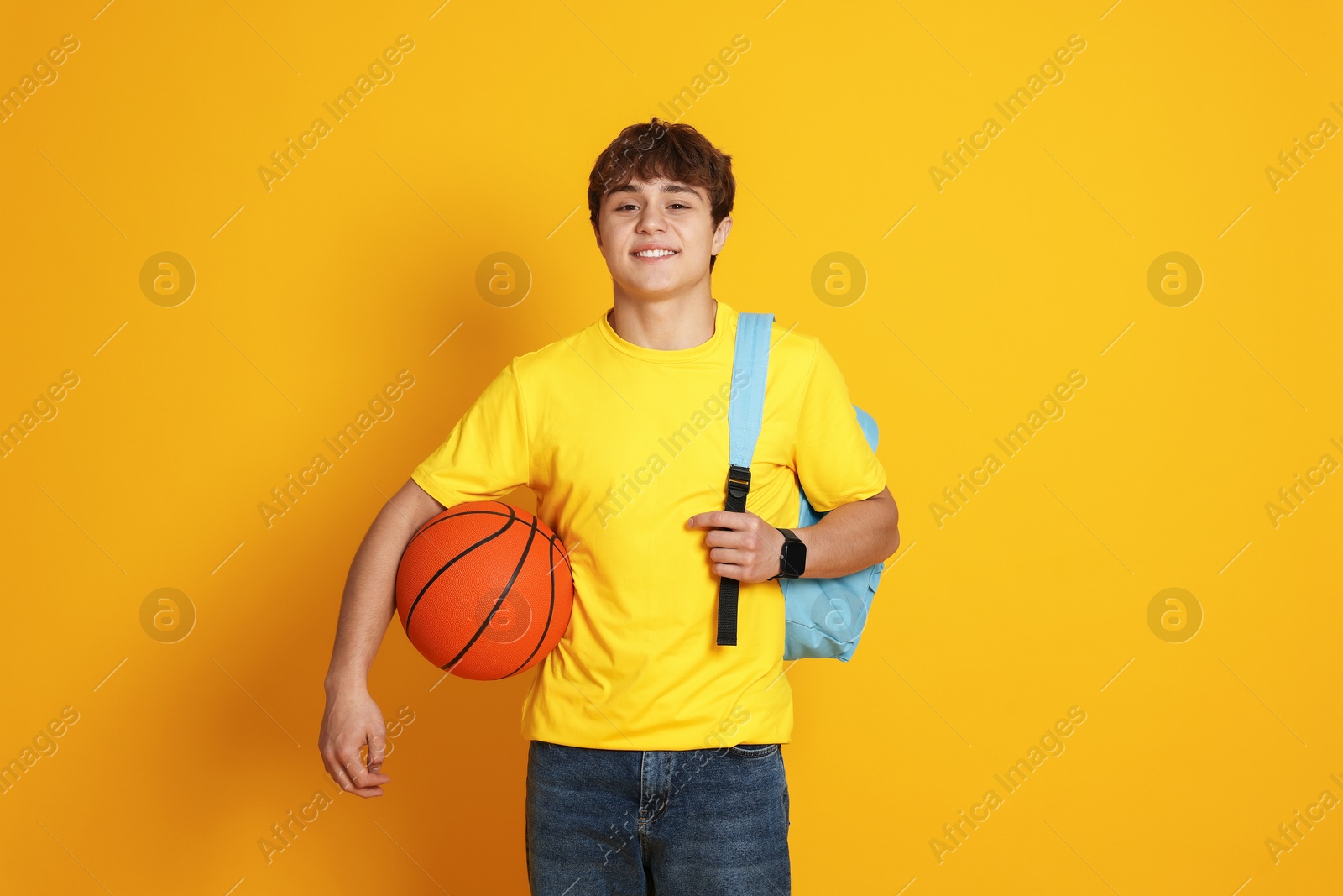 Teenage boy with basketball on yellow background Photo of Teenage boy with basketball on yellow background