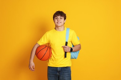 Photo of Teenage boy with basketball on yellow background