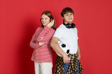 Photo of Teenagers with headphones and soccer ball on red background