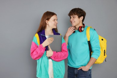 Photo of Teenagers with backpack and laptop on grey background