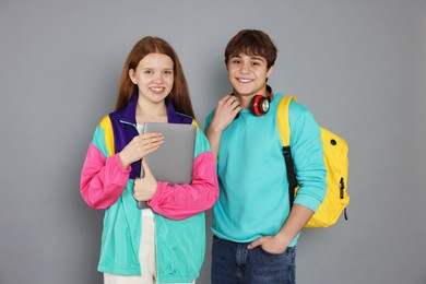 Photo of Teenagers with backpack and laptop on grey background