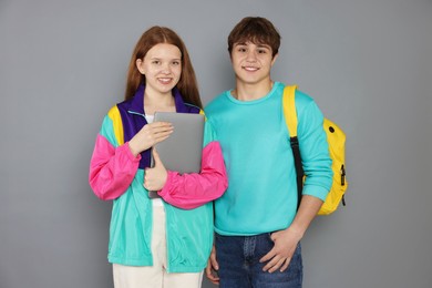 Photo of Teenagers with backpack and laptop on grey background